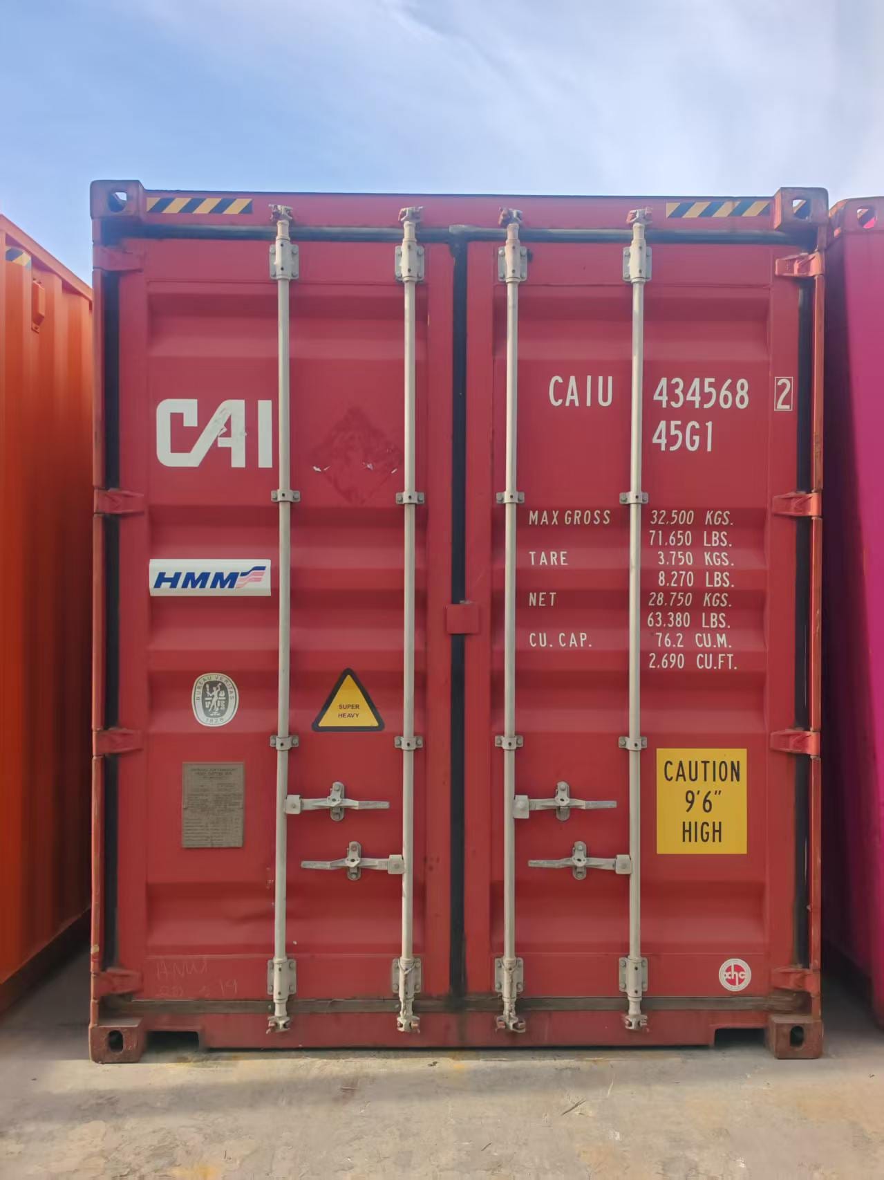 A red export container standing with its doors closed and locking bars in place, ready to be collected