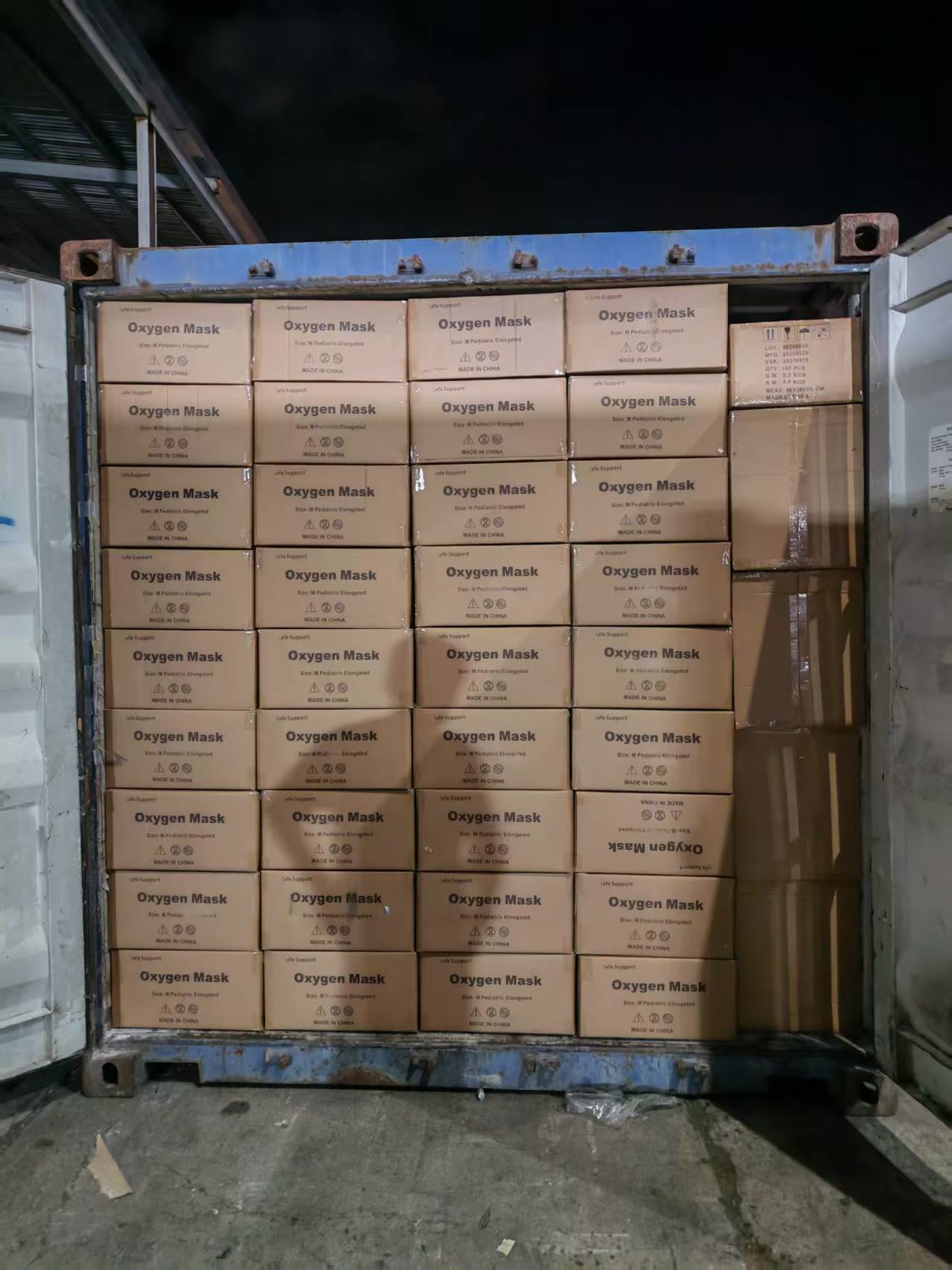 Container one, loaded after dark: cartons of medical supply products stacked in neat rows up to the door