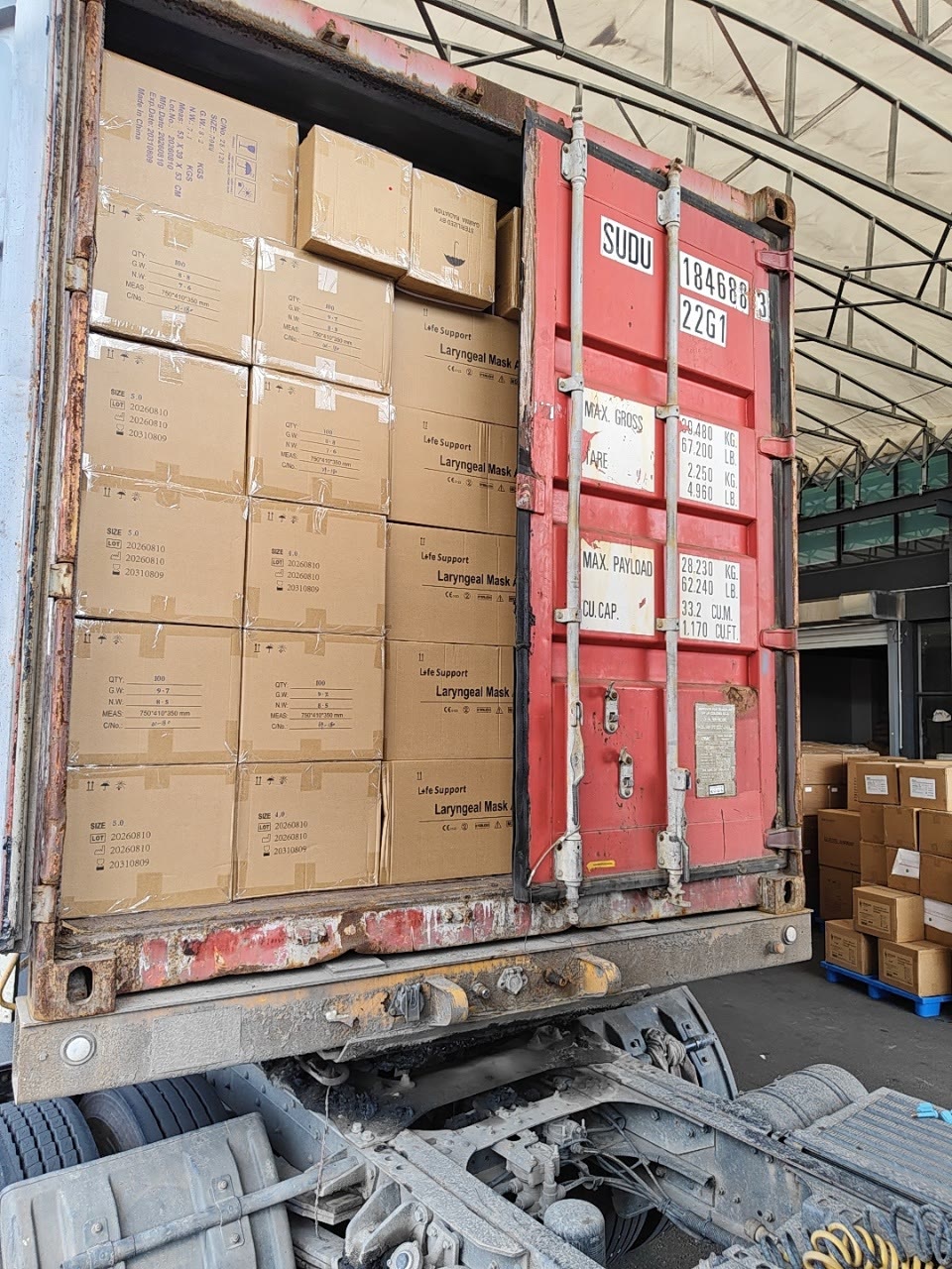Container four: cartons loaded up to the red door, seen from the rear of the truck